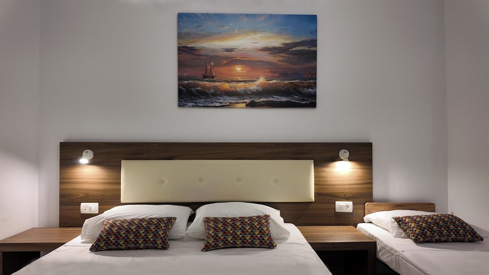 Ruime hotelkamer met wit beddengoed en balkon in Hotel Santorini