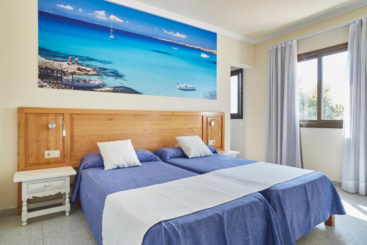een slaapkamer met een groot bed met blauwe lakens bij Invisa Aparthotel Casa Luis in Santa Eularia des Riu