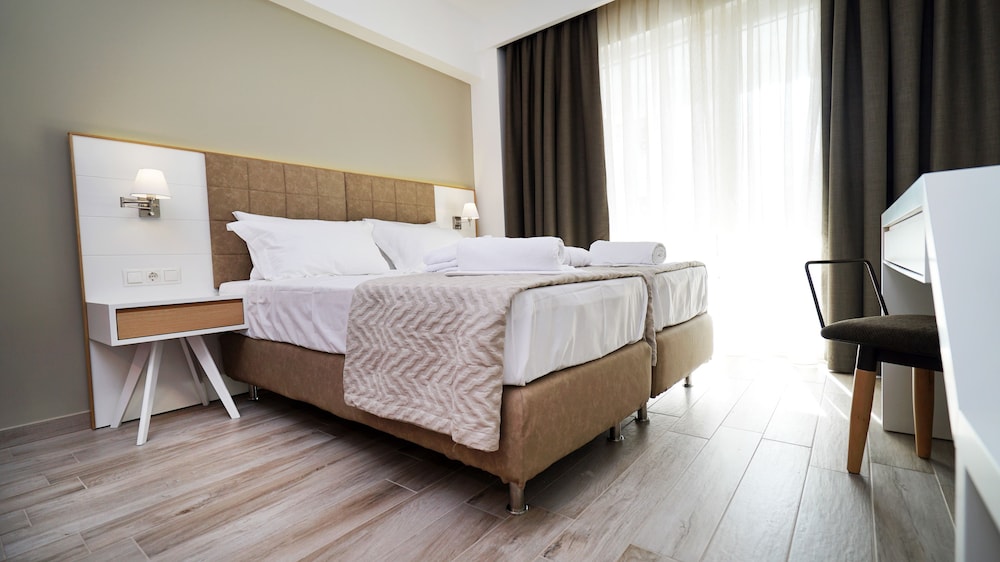 Slaapkamer met bedlinnen en raamuitzicht in Olympus Thalassea
