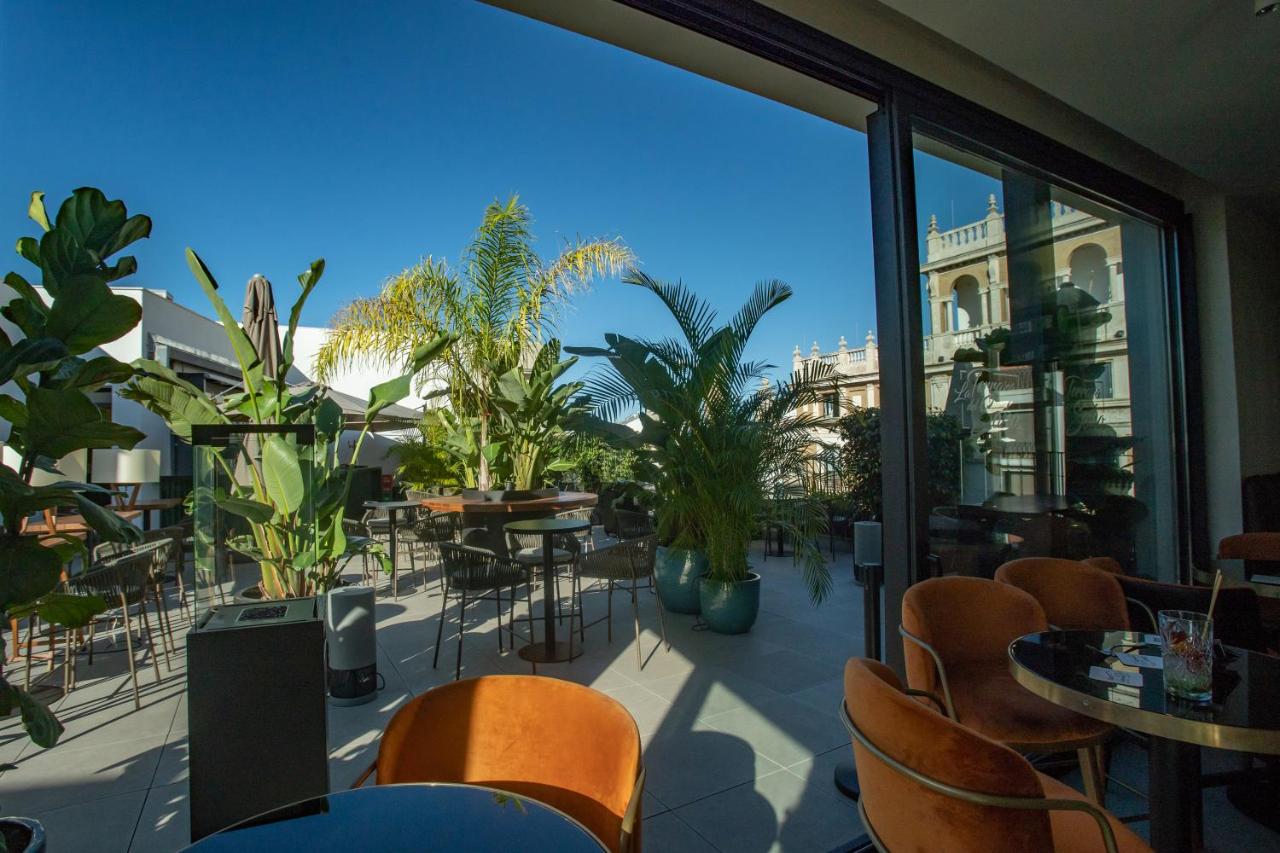 a patio with tables and chairs and a large window at Soho Boutique Catedral in Seville