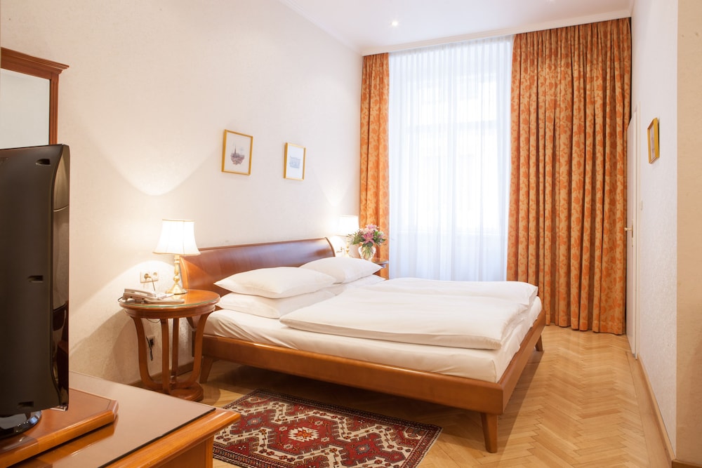 Ruime hotelkamer met stijlvolle meubels en schilderijen
