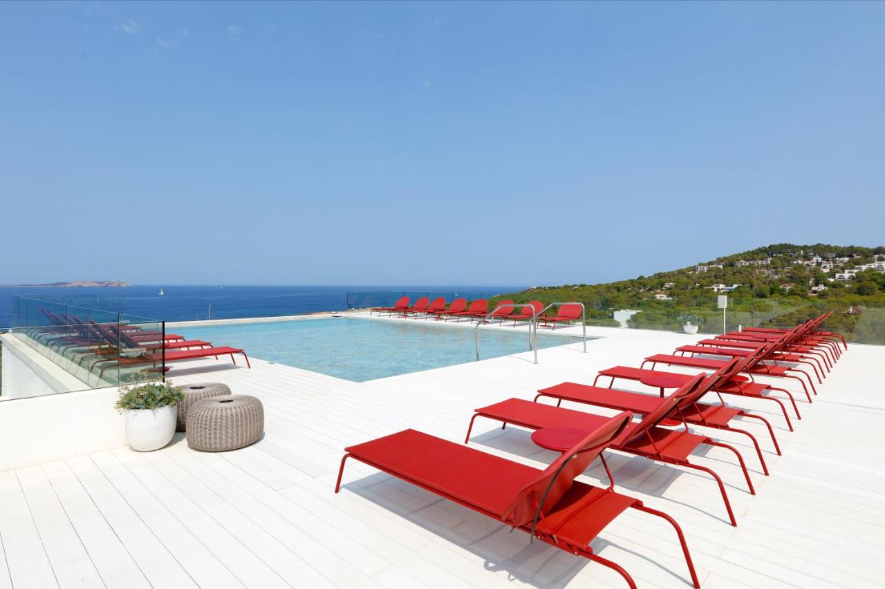 een rij rode stoelen naast een zwembad bij TRS Ibiza Hotel - Adults Only in San Antonio